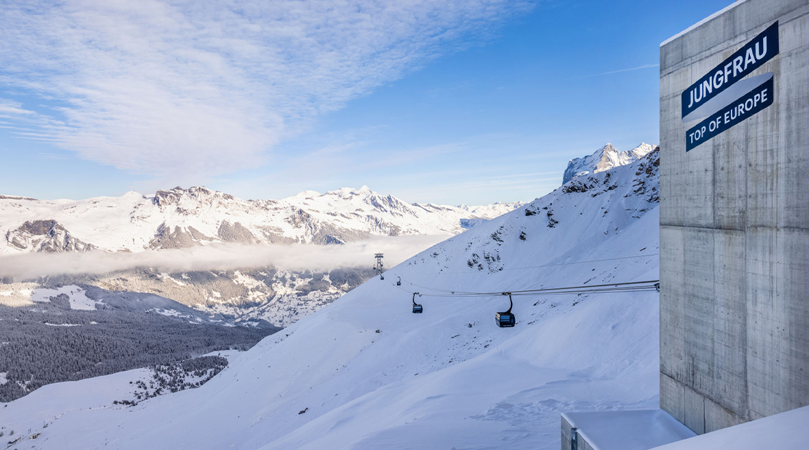 The view down from Top of Europe railway station to a snow-covered valley with the Eiger Express gondola cutting across the mountain
